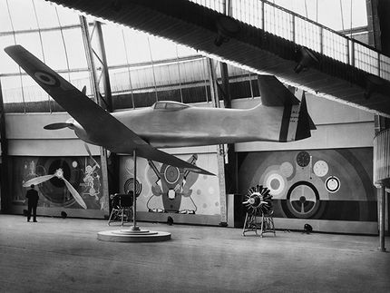 Konstnärsparet Robert och Sonia Delaunay ställde ut några av sina färgsprakande verk i Luftfartspaviljongen. Här ser man i bakgrunden Sonias tre målningar Propeller, Motor och Instrumentpanel. De finns i original på skissernas museum i Lund.
